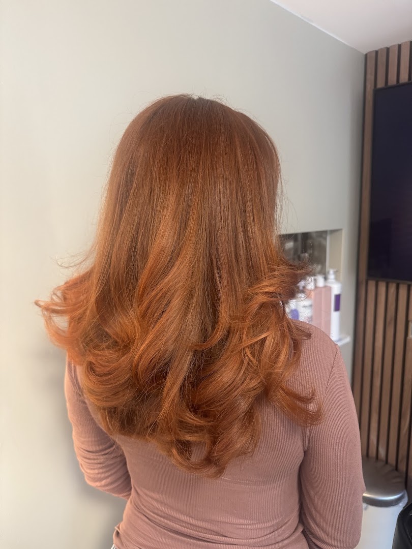 Lang koperkleurig haar met volle curls, resultaat van een kleurbehandeling bij Hair Boutique By Bo